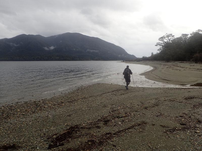 hiker walking along a gravel lakeside