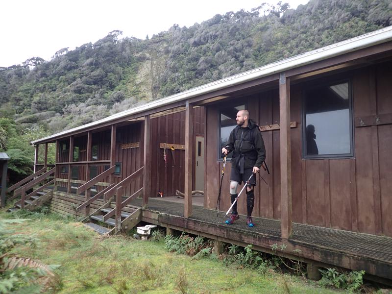 hiker standing in front of a wooden backcountry hut
