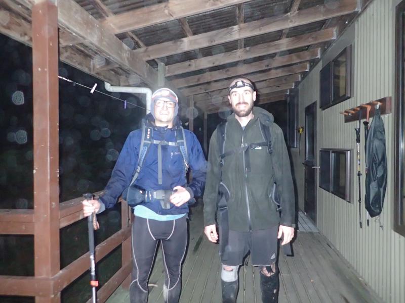 2 hikers outside a hut in the dark