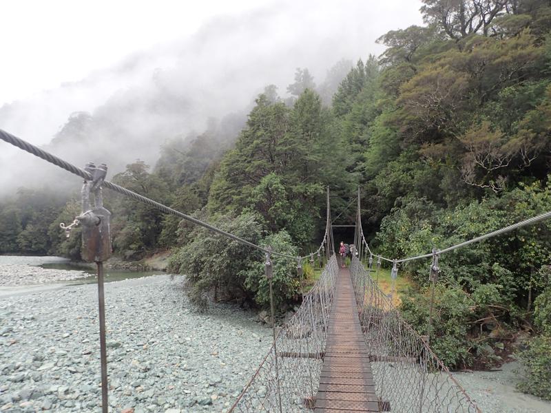 a narrow swing bridge over a small river