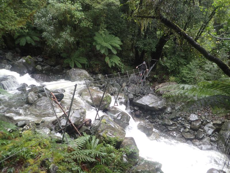 hiker crossing a river on a walkwire