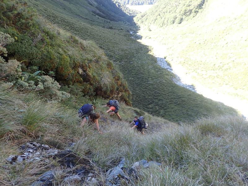 3 hikers climbing steeply above a valley
