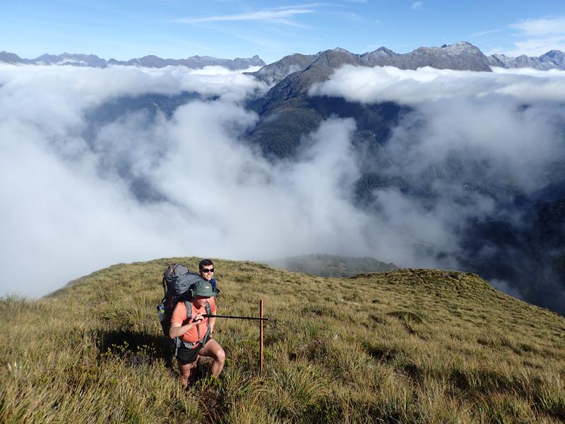 2 hikers admiring the view as clouds clear and mountains emerge