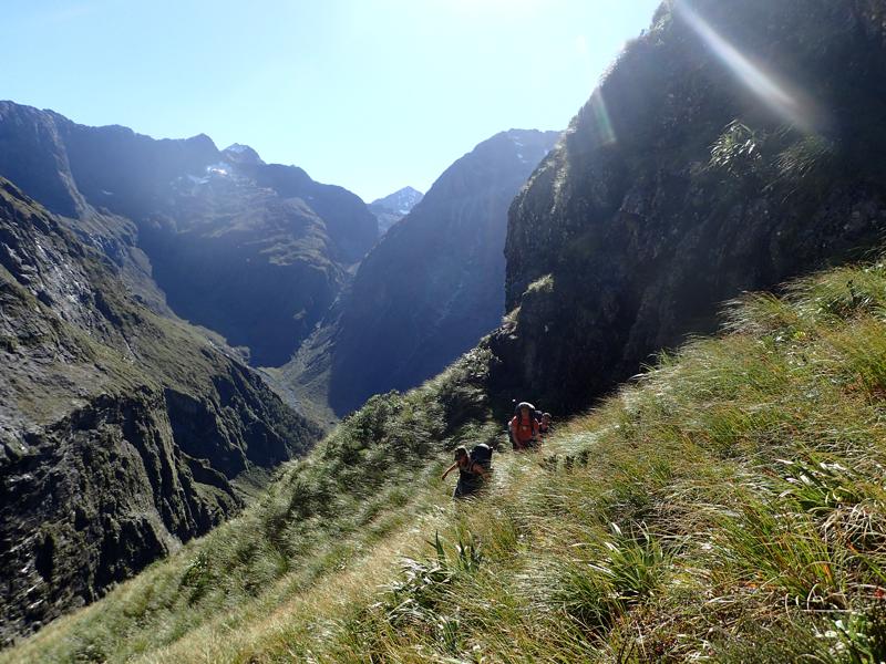 3 hikers contouring on a steep grassy slope