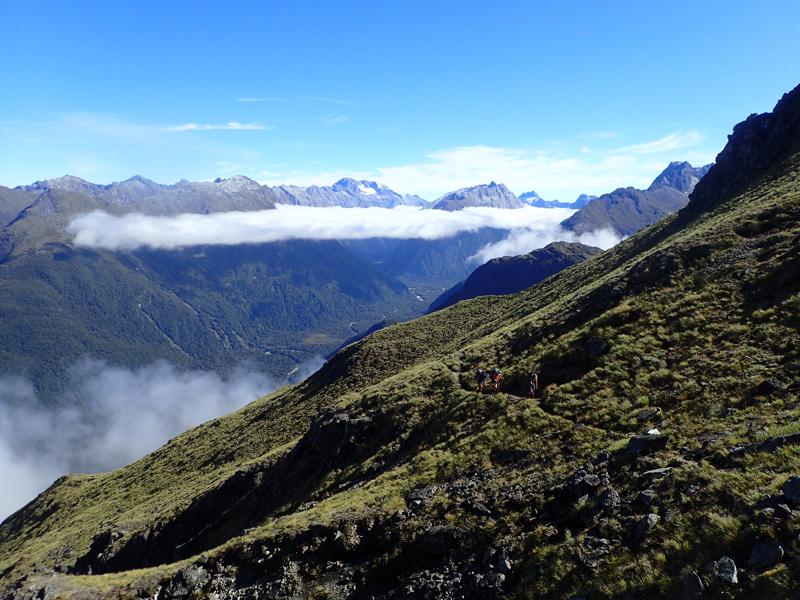 mountains in the distance and hikers contouring along a track