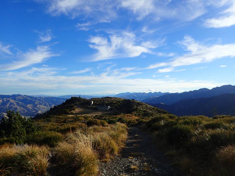 looking down on mount fyffe hut in the afternoon sun with mountains in the distance