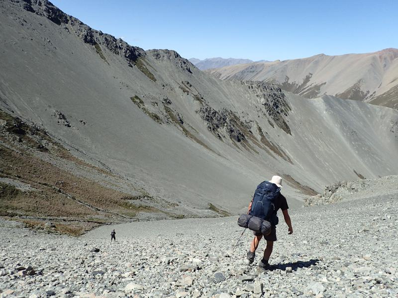 2 hikers descending a scree slope into a valley