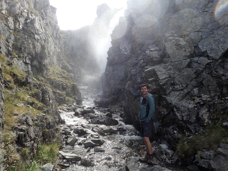 a hiker in a narrow gorge with spray beyond