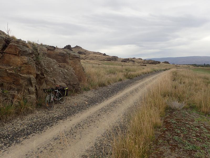 Bike on a gravel track with rocks around and cloudy sky