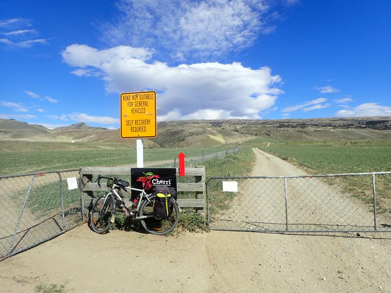 Bike resting beside a gravel track with fields and then hills beyond