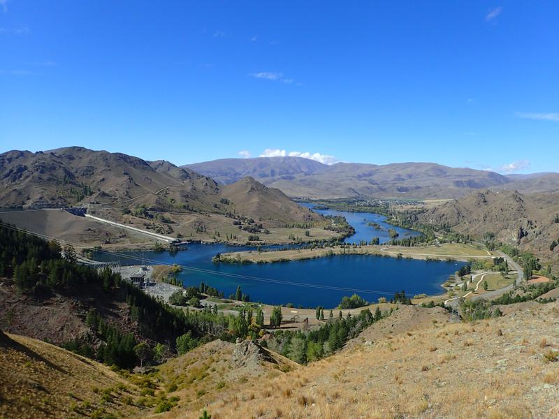 Dam and river beyond viewed from above with mountains