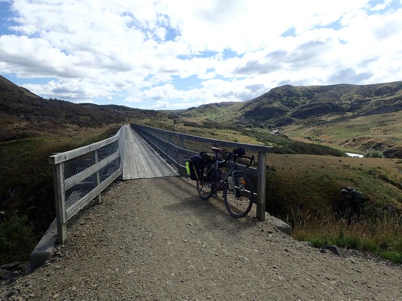 Bike on gravel track with narrow wooden bridge