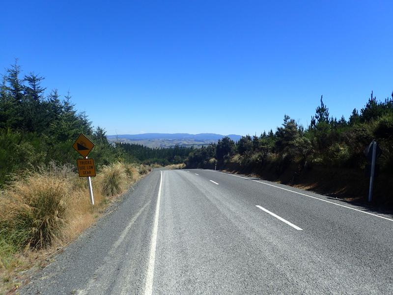 Road going downhill with blue sky above