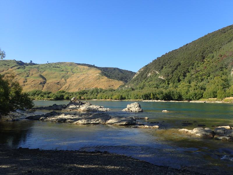 A wide river with rocks in sunshine