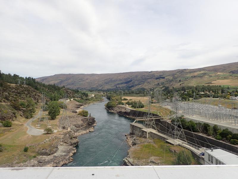 View from the top of a dam, river below and electricity power lines on the side